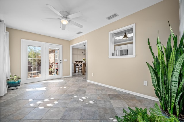 tiled spare room with visible vents, ceiling fan, and baseboards