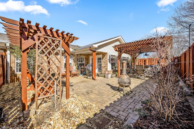 view of patio with fence, a fire pit, and a pergola