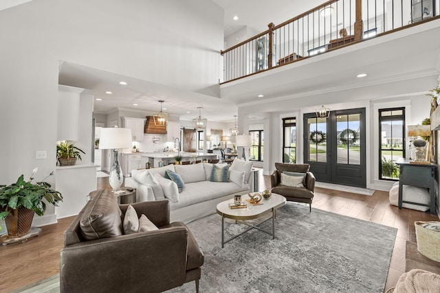 living area with recessed lighting, wood-type flooring, crown molding, and french doors