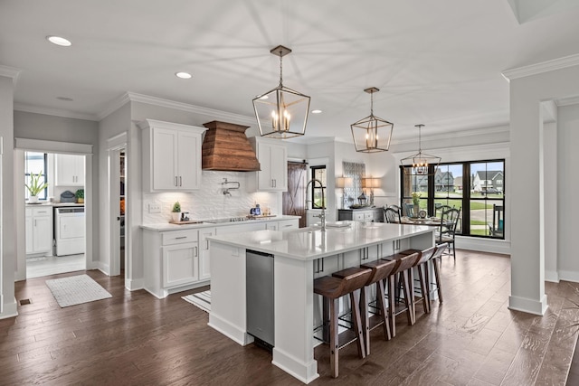 kitchen with an island with sink, washer / clothes dryer, an inviting chandelier, premium range hood, and a sink