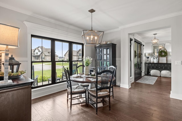 dining room with dark wood-style floors, a chandelier, and crown molding