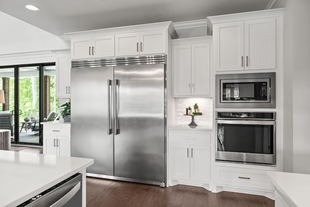 kitchen with white cabinetry, light countertops, backsplash, and built in appliances