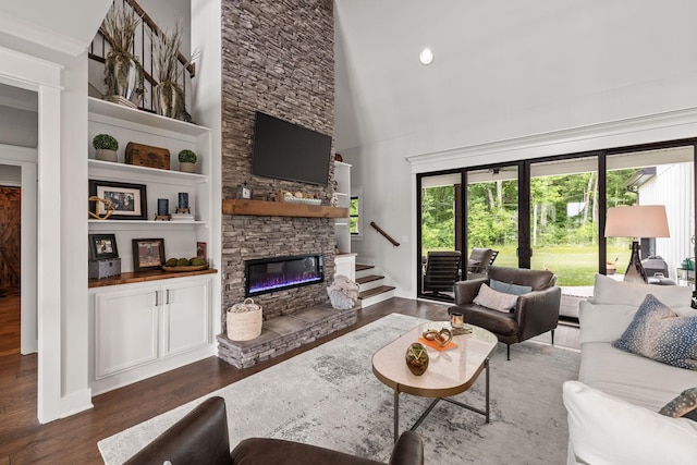 living area with dark wood-style floors, a high ceiling, a fireplace, and stairs