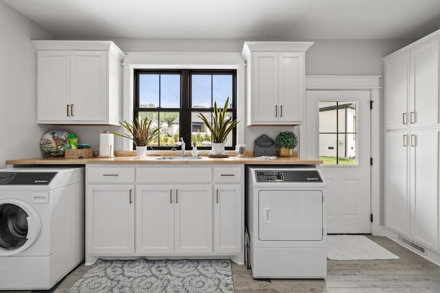 washroom with a healthy amount of sunlight, visible vents, separate washer and dryer, and a sink