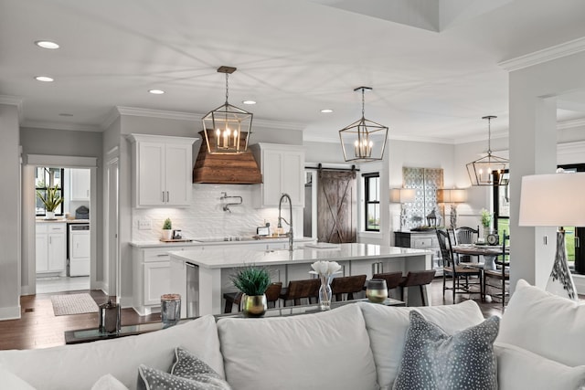 kitchen featuring a barn door, dark wood finished floors, open floor plan, a kitchen island with sink, and white cabinetry