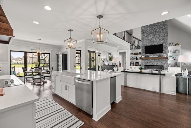 kitchen with a sink, an inviting chandelier, a fireplace, and stainless steel dishwasher