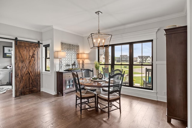 dining space featuring a barn door, wood finished floors, baseboards, an inviting chandelier, and crown molding