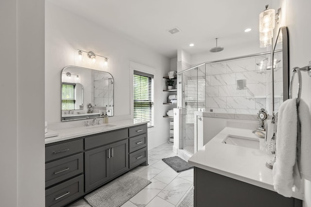 bathroom with visible vents, a sink, marble finish floor, a shower stall, and two vanities