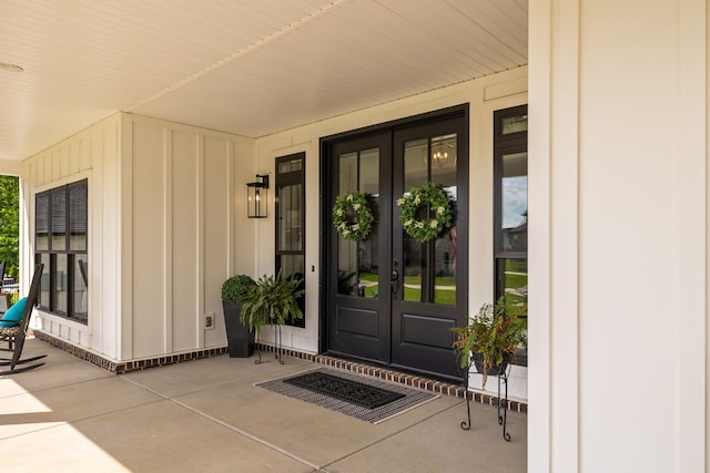 doorway to property with covered porch, french doors, and board and batten siding