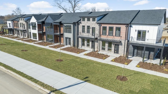 view of front facade featuring stone siding, a residential view, a front lawn, and board and batten siding