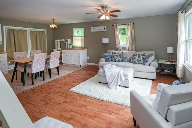 living area featuring baseboards, ceiling fan, and light wood-style floors