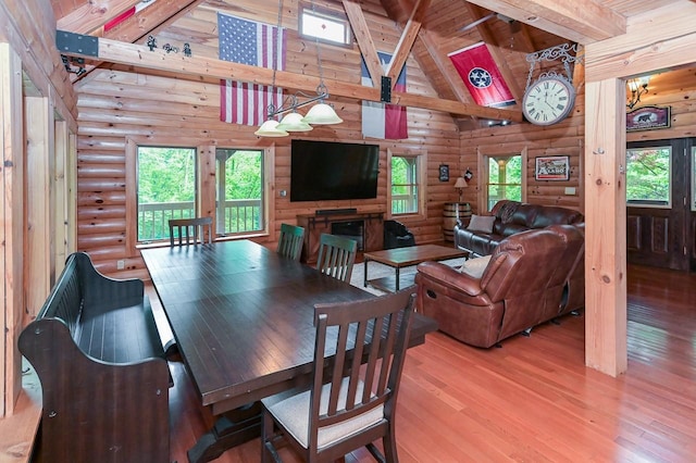 dining area featuring light wood-type flooring, a healthy amount of sunlight, high vaulted ceiling, and beam ceiling