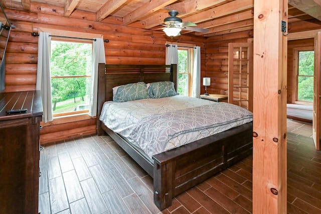 bedroom with log walls, wood finish floors, and beam ceiling