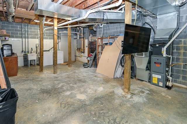 unfinished basement with a sink, concrete block wall, and washer and dryer