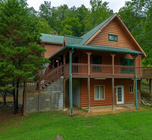 back of property with roof with shingles, a yard, and stairway