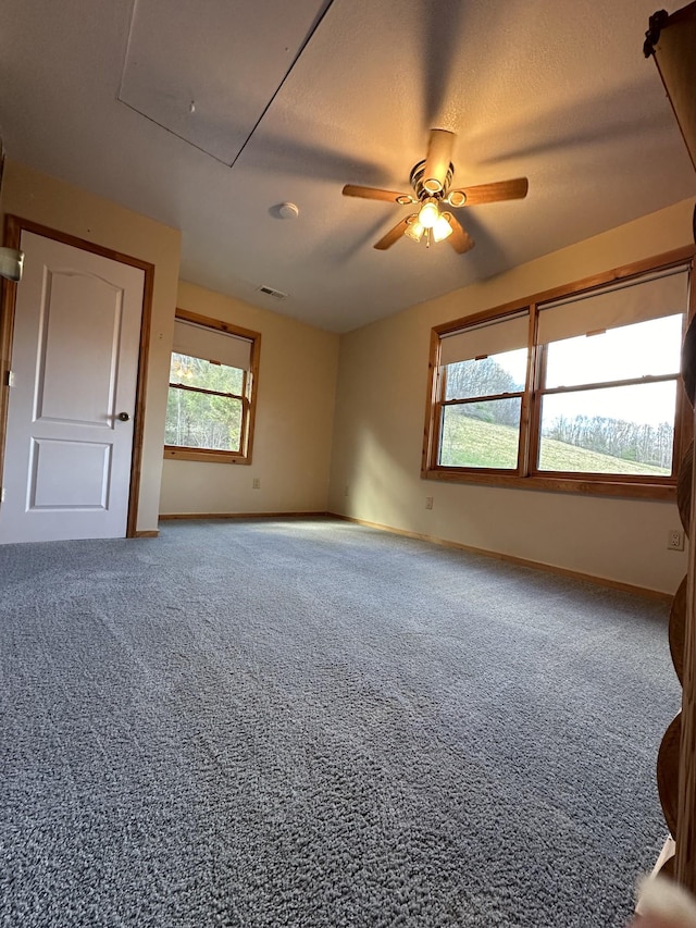 unfurnished room with ceiling fan, a textured ceiling, baseboards, carpet, and attic access