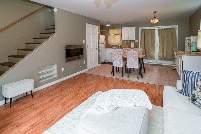 dining space with baseboards, light wood finished floors, and stairs