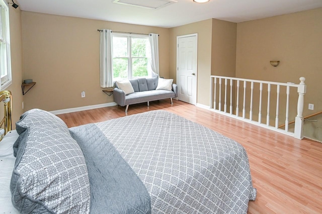 bedroom featuring attic access, baseboards, and wood finished floors