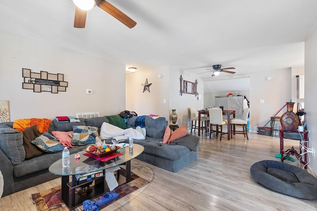 living area with visible vents, ceiling fan, and wood finished floors