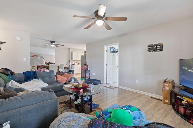 living area featuring light wood-style floors, visible vents, baseboards, and a ceiling fan