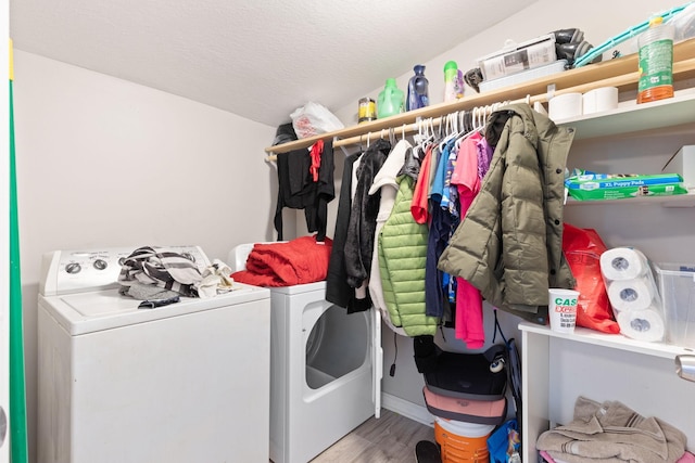 clothes washing area with a textured ceiling, laundry area, separate washer and dryer, and wood finished floors