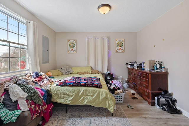 bedroom with electric panel and wood finished floors