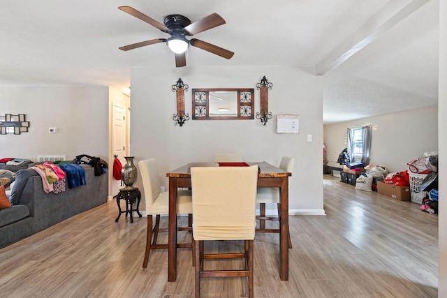 dining room with a ceiling fan, visible vents, beamed ceiling, and light wood-style flooring