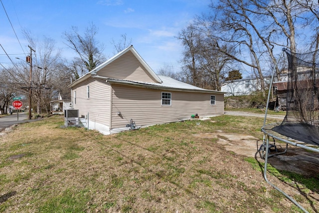 view of home's exterior with a trampoline, metal roof, and a lawn