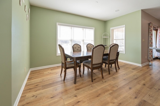 dining space with light wood-style flooring and baseboards