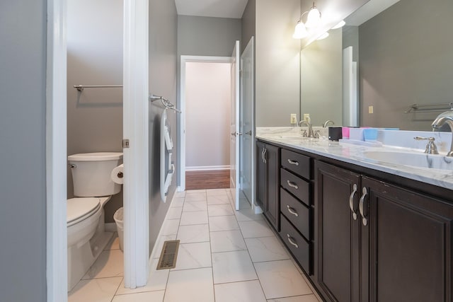 bathroom with double vanity, a sink, toilet, and baseboards