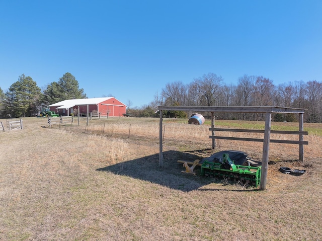 view of yard featuring an outbuilding, a garage, an outdoor structure, fence, and driveway