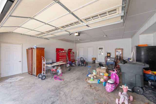 garage with a garage door opener and freestanding refrigerator