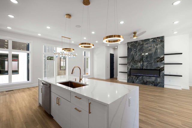 kitchen with open floor plan, a sink, light wood finished floors, and stainless steel dishwasher