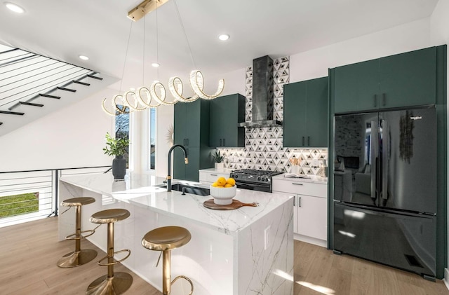 kitchen with light wood-style flooring, a sink, wall chimney exhaust hood, black appliances, and plenty of natural light