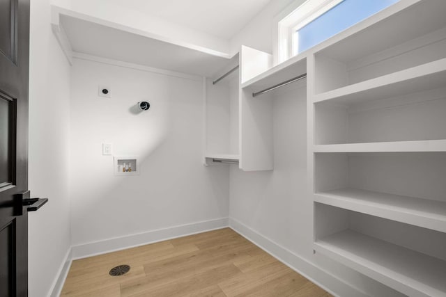 interior space with light wood-style flooring, laundry area, washer hookup, baseboards, and electric dryer hookup