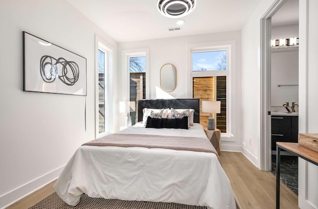 bedroom featuring wood finished floors, visible vents, and baseboards