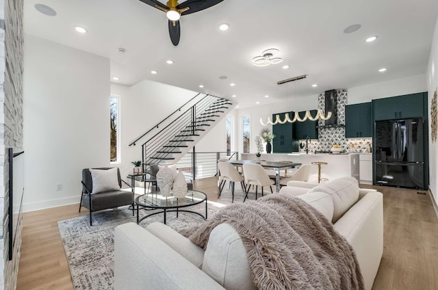 living area featuring light wood-type flooring, stairway, and recessed lighting