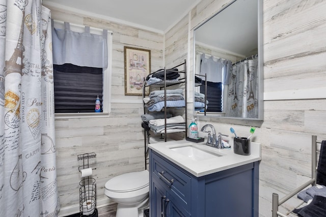 full bath featuring toilet, vanity, and wooden walls