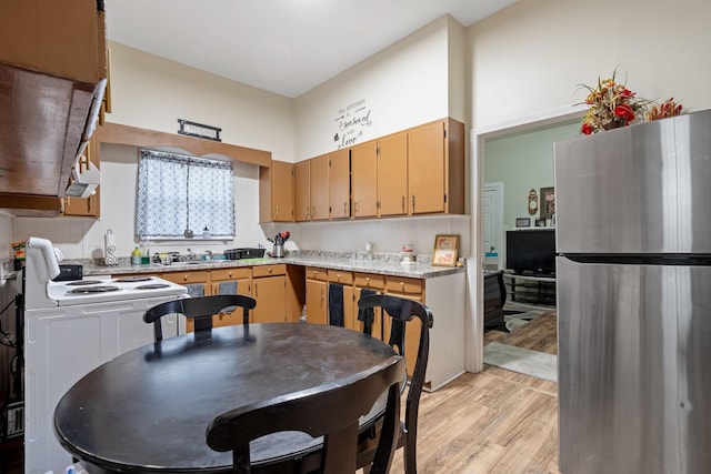 kitchen with light wood finished floors, tasteful backsplash, electric stove, freestanding refrigerator, and light countertops