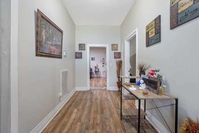 hallway featuring wood finished floors, visible vents, and baseboards