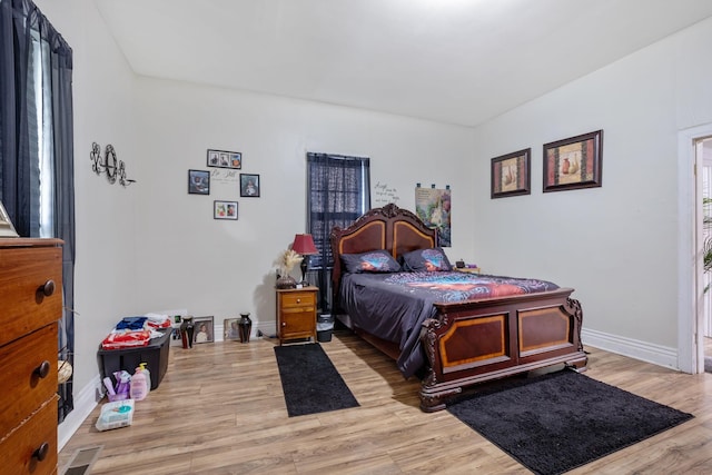 bedroom with visible vents, light wood-style flooring, and baseboards