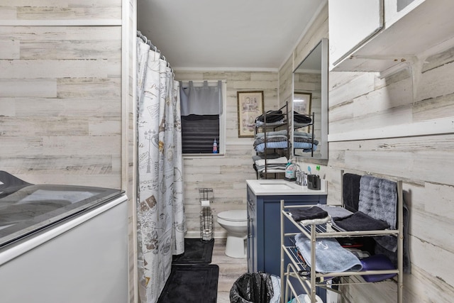 full bathroom featuring a shower with shower curtain, toilet, wooden walls, vanity, and wood finished floors