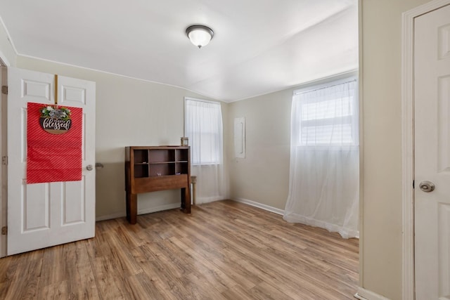 unfurnished bedroom with lofted ceiling, light wood-style flooring, and baseboards