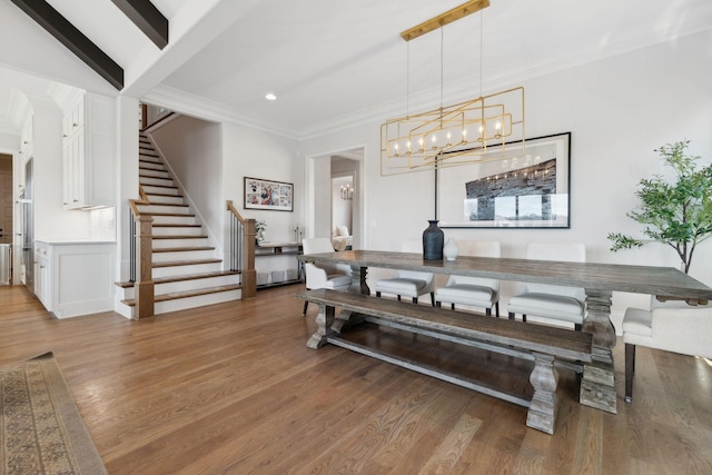 dining space with stairs, ornamental molding, wood finished floors, and beam ceiling