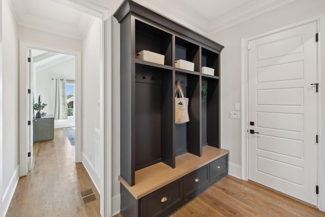 mudroom featuring light wood-style flooring, visible vents, baseboards, and ornamental molding