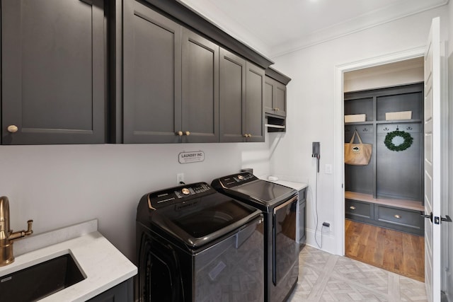 washroom featuring cabinet space, parquet floors, crown molding, separate washer and dryer, and a sink