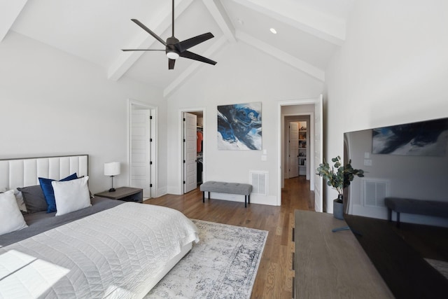 bedroom featuring visible vents, a spacious closet, wood finished floors, high vaulted ceiling, and beamed ceiling