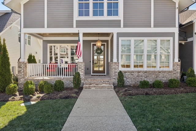 property entrance with a porch and brick siding