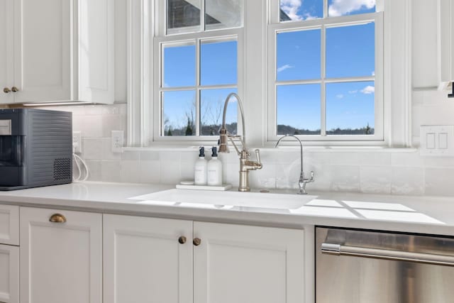 kitchen with a sink, white cabinetry, light countertops, backsplash, and dishwasher