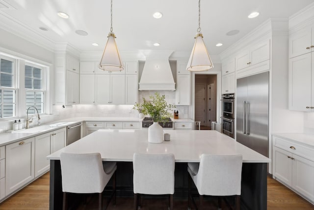 kitchen featuring tasteful backsplash, custom range hood, appliances with stainless steel finishes, a center island, and light countertops